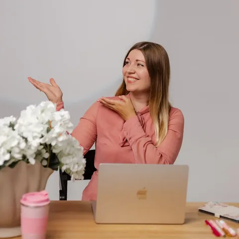 Martyna Siewert, mentorka swobodnego mówienia po angielsku, uśmiechnięta przy biurku z laptopem, wskazuje ręką w stronę quizu
